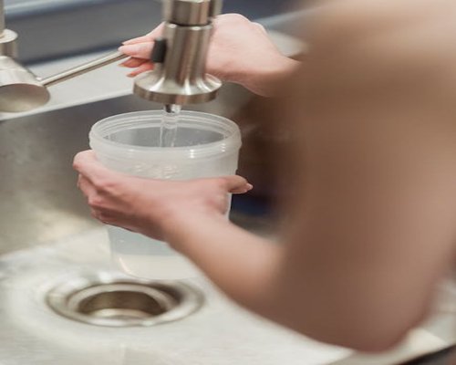 person filling reusable water bottle at office cooler